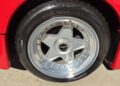 Close-up of a polished silver alloy wheel with a five-spoke design, mounted with a Pirelli P Zero tire on a red Ferrari F40.