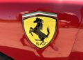 Close-up of a Ferrari logo featuring a black prancing horse on a yellow shield with the letters "S F" on a Ferrari F40's red body—an iconic detail that collectors seek at auction.