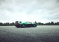 A green Rimac Nevera sports car with a rear spoiler is parked on an empty asphalt lot, forested background behind it and clouds above—the fastest EV that breaks records even at rest.