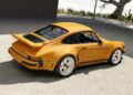 A yellow sports car with a rear spoiler is parked on a concrete surface near a modern building, as the California-based singer unveils their latest reimagined Porsche 911 Carrera Coupes at Goodwood.