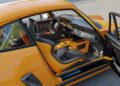 A yellow sports car with the driver's door open reveals a black and gray interior, bucket seats, and a manual gear shift, echoing the flair of California-based singer's latest reimagined Porsche 911 Carrera Coupes at Goodwood.