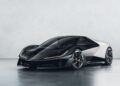 A sleek, modern black and silver sports car—reminiscent of the spirit Lotus will channel to honor F1 legends Senna and Clark at Goodwood—is parked indoors against a plain, light-colored wall.