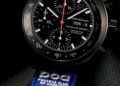 A black chronograph wristwatch with a blue fabric strap featuring "Porsche Club of America" branding, celebrating the Limited-Run 2026 911 Carrera T Club Coupe and showing the time as 10:09:46 and date as Sunday the 6th.