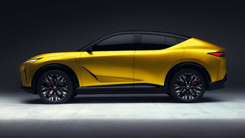 A yellow, modern, all-electric SUV coupe parked in a studio with a dark background, shown in a side profile view.