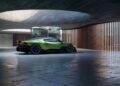 A green Bugatti sports car featuring a powerful W16 engine is parked in a modern, concrete garage with wooden slats and large circular skylights.