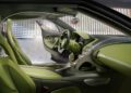 A luxury Bugatti car interior featuring green and black leather seats, a matching dashboard, and metallic accents, with the driver’s door open in a modern garage setting—highlighting its powerful W16 engine.
