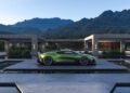 A green Bugatti sports car, featuring the powerful W16 engine, is parked on a platform surrounded by water, with modern buildings and mountains in the background under a clear sky.