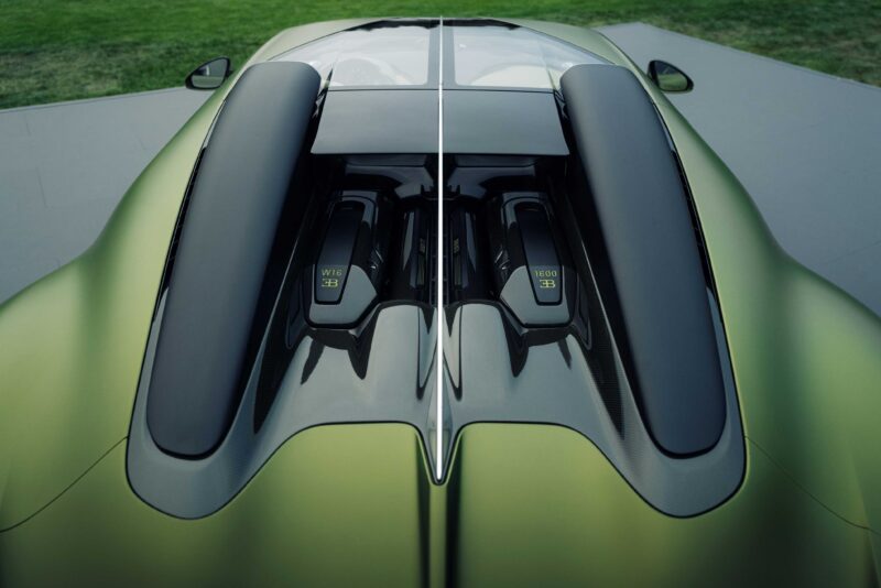 A close-up, top-down view of the engine cover and air intakes on a green sports car at The Quail, showcasing carbon fiber detailing and V8 engine labeling during its first public appearance.