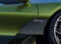 Close-up of a green sports car with a carbon fiber accent, side mirror, "Downforce" badge, Michelin tire, and subtle Brouillard reflections under a blue sky—evoking the spirit of legendary W16 Bugatti engineering.