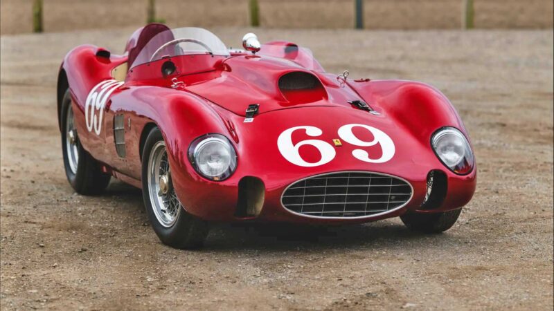 A vintage red racing car with the number 69 painted on the hood and sides, parked on a dirt surface, reminiscent of classics seen at the 2025 RM Sotheby's Monterey Auction: Top 10 Results And Highlights.