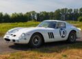 A factory white Ferrari 250 GTO with the number 10 on the door is parked on a rural road, surrounded by grass and trees under a clear sky—a stunning sight reminiscent of a Mecum Kissimmee Auction classic.