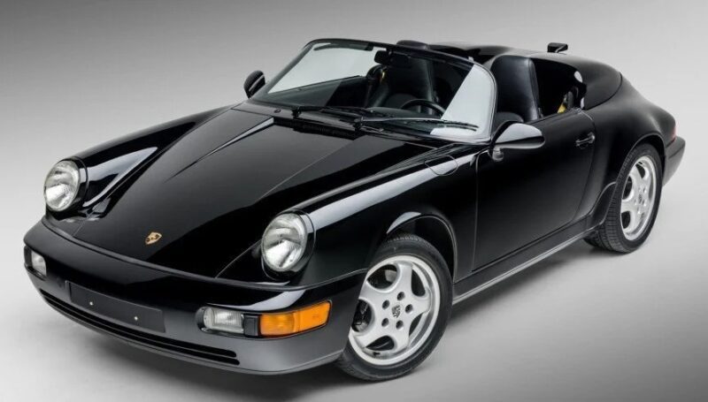 A black Porsche convertible sports car is shown in a studio setting, viewed from the front-left angle, with silver rims and the top down—perfect for those seeking 90s cars for sale and a touch of nostalgia.