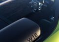 Close-up of a Bugatti’s green rear wing with "W16" embossed, revealing a partial view of the interior through the window, including the steering wheel and dashboard.