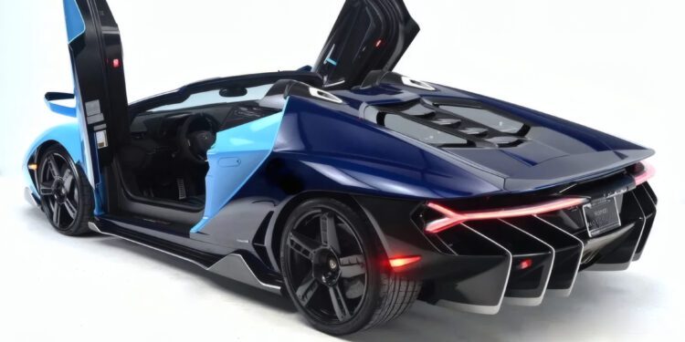 A blue and black Lamborghini Centenario Roadster with its scissor doors open, viewed from the rear on a white background. Only 10 in the U.S.: this luxury sports car is an ultra-rare masterpiece hitting the market.