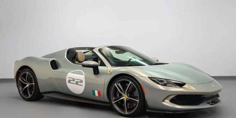 A silver Ferrari convertible sports car in classic Ferrari colors, with the number 22 on the door and an Italian flag decal, is parked indoors on a gray floor.