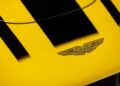 Close-up of a yellow Aston Martin Valkyrie car hood featuring black racing stripes and the iconic Aston Martin winged logo, available for sale at O’Gara Coach.