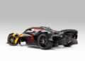 An ultra-rare black and yellow Aston Martin Valkyrie sports car with red accents and the number 001, photographed in a studio with a gray background.