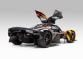 An ultra-rare Aston Martin Valkyrie, finished in black and orange with its gullwing doors open, is viewed from the rear left side against a plain light background.