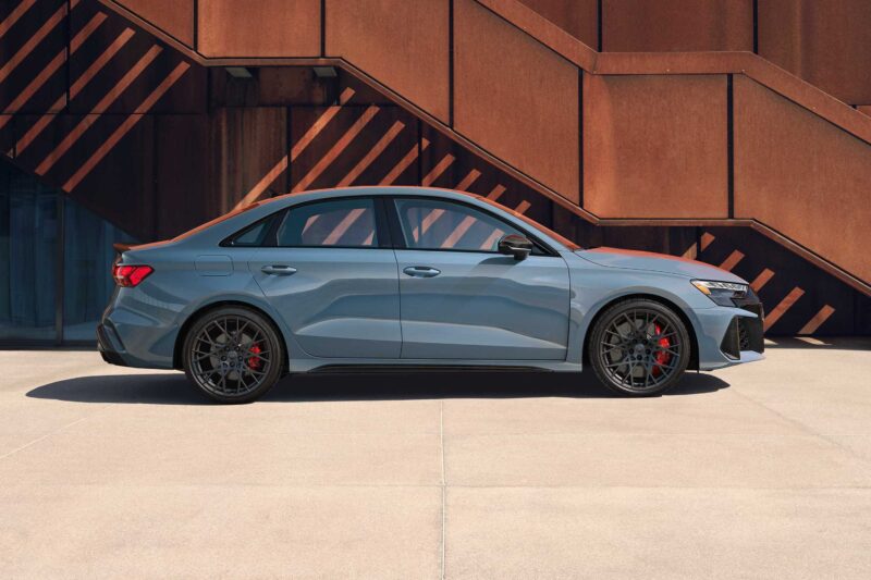 A gray sports sedan—The Last Surviving 5-Cylinder On Sale Today Packs A Punch—sits on black wheels, parked in front of a modern building with rust-colored metal stairs.
