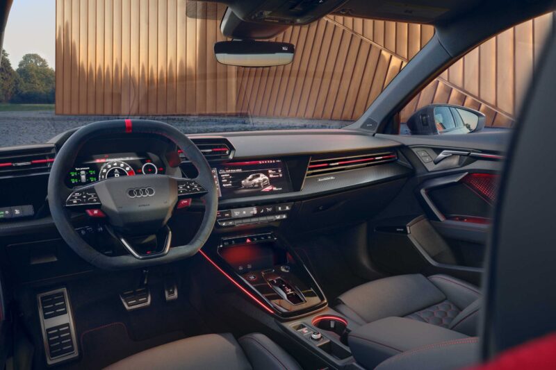 Interior view of a modern Audi car featuring a digital dashboard, multifunction steering wheel, and red ambient lighting accents—the last surviving 5-cylinder on sale today packs a punch behind the wheel.