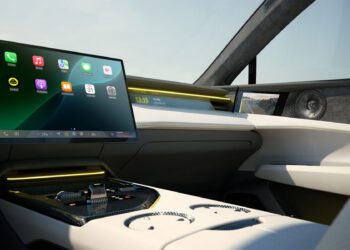 Modern car interior featuring a large central touchscreen display, digital controls, and white leather seats with yellow accents.