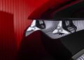 Close-up of the Mercedes-Benz Vision V concept’s modern headlight with angular design features, set against a red, ribbed background, capturing van luxury in every detail.