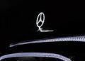 Illuminated Mercedes-Benz logo on the hood of a black car, with reflections of LED lights accentuating the vehicle's surface—showcasing concept elegance inspired by the Mercedes-Benz Vision V.