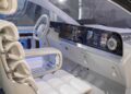 Futuristic car interior with white seats, a large digital dashboard display, and a minimalist steering wheel, the Mercedes-Benz Vision V concept preview showcases modern design and advanced technology in van luxury.