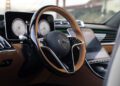 Close-up view of a Mercedes-Maybach S 680 steering wheel and dashboard with digital displays and control screens, featuring a bridge in the blurred background—an interior crafted for this limited edition masterpiece.