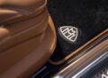 Close-up of a brown leather car seat in the limited edition Mercedes-Maybach S 680, next to a black floor mat featuring the Maybach logo in silver embroidery—part of the exclusive Emerald Isle collection.