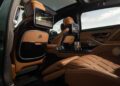 The interior of the limited edition Mercedes-Maybach S 680 boasts tan leather seats, a reclining footrest, built-in screens, glass holders, and ambient lighting inspired by the elegance of Emerald Isle.