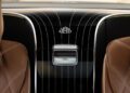 Close-up view of a limited edition Mercedes-Maybach S 680's rear center console with the Maybach logo, black paneling, silver accents, and brown leather seats on either side.