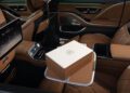 Luxurious car interior with tan leather seats, digital screens, and a white Maybach-branded box on a fold-out tray in the rear passenger area of the limited edition Mercedes-Maybach S 680 Emerald Isle.
