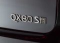 Close-up of a vehicle badge showing "QX80 S 4WD" on a dark-colored surface, highlighting how the 2026 INFINITI QX80 introduces SPORT Grade and ups the luxury game.