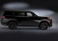Side view of a black 2026 INFINITI QX80 SPORT, featuring dark wheels and photographed against a dark background with subtle lighting that elevates the luxury game by highlighting the vehicle’s striking contours.