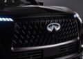 Close-up of the front grille and emblem of a black 2026 INFINITI QX80, featuring a distinctive diamond pattern, illuminated headlights, and hints of the new SPORT Grade that ups the luxury game.