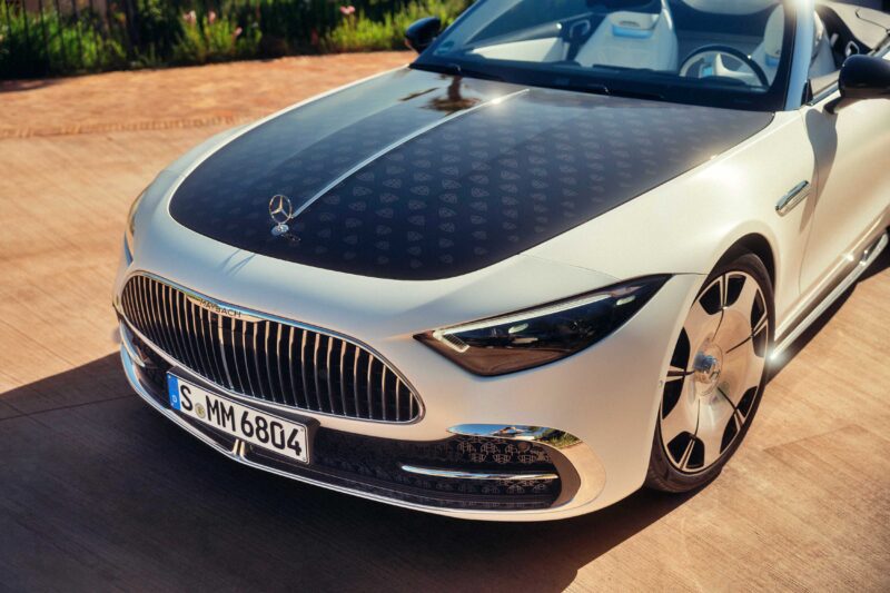 A white 2026 Mercedes-Maybach SL 680 convertible with a patterned black hood is parked on a sunlit paved surface, showcasing the refined elegance of this ultra-luxury roadster.