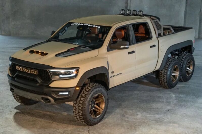 A tan six-wheeled pickup truck with custom off-road modifications, a true standout among unique custom cars, is parked indoors on a concrete floor.