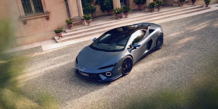 A grey Lamborghini Temerario is parked on a gravel driveway in Porto Cervo, in front of a building with columns, potted plants, and large windows.