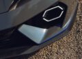 Close-up of a Lamborghini's front bumper with a geometric air intake vent, carbon fiber detailing, and gravel ground in the background—true Temerario spirit.
