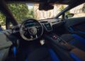 Interior view of a Lamborghini sports car in Porto Cervo, highlighting the steering wheel, digital dashboard, center touchscreen, and blue-accented Bespoke Temerario seats.
