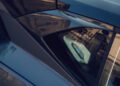 Close-up of a Lamborghini’s rear window and carbon fiber body panel, reflecting buildings in Porto Cervo, with a small Bespoke Temerario badge featuring a colorful emblem inside the glass.