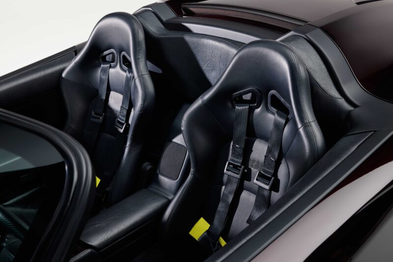 Black leather racing seats with harnesses in a convertible sports car interior, viewed from above—reminiscent of the style unveiled at Monterey Car Week.