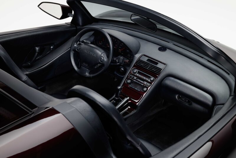 Interior view of a convertible Acura NSX, showcasing the dashboard, steering wheel, center console, and leather seats with the top down—perfect for someone like Tony Stark cruising through Monterey Car Week.