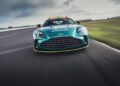 A green Aston Martin Vantage S Safety Car speeds down the racetrack during a Formula 1 event, captured from the front with blurred surroundings highlighting its rapid motion.