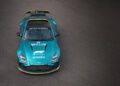 A teal Aston Martin Vantage Safety Car with official Formula 1 branding and a roof-mounted light bar is parked on an asphalt surface, viewed from above.