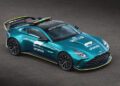 A teal Aston Martin Vantage S Safety Car with F1 branding, roof lights, and yellow accents is parked on a dark surface, viewed from above.