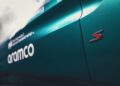 Close-up of a teal Aston Martin Vantage S car door with a red "S" badge and white "aramco" logo, showing part of a Safety Car sponsorship decal.