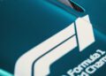 Close-up of a teal Aston Martin Formula 1 car, featuring prominent FIA and Formula 1 World Championship logos along with a carbon fiber air vent.