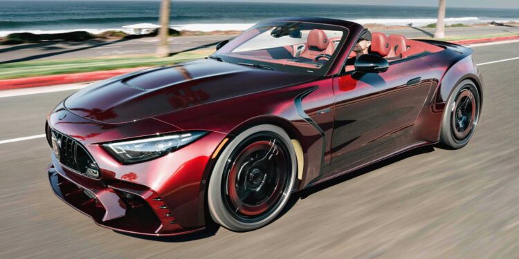 The BRABUS Rocket GTC Deep Red breaks cover at Pebble Beach, as a red convertible sports car with a black grille and red interior drives along a coastal road, ocean and palm trees in the backdrop—boasting 1000 HP and an all-carbon body.